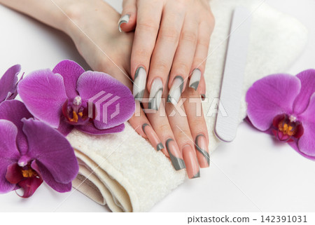 Woman receiving manicure treatment with orchids and nail file 142391031