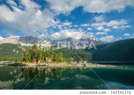 Mountain reflection in Eibsee lake through forest trees in Bavaria Germany Mountain reflection in Eibsee lake through forest trees in Bavaria Germany 142391178