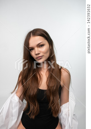 Young woman looking directly at the camera, showing a confident and natural expression, with long brown hair Young woman looking directly at the camera, showing a confident and natural expression, with long brown hair 142391632