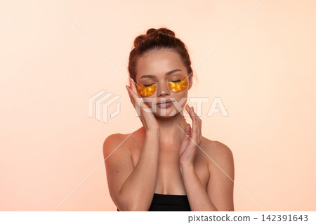 Woman applying gold hydrogel under eye patches for skin hydration and anti-aging beauty routine Woman applying gold hydrogel under eye patches for skin hydration and anti-aging beauty routine 142391643