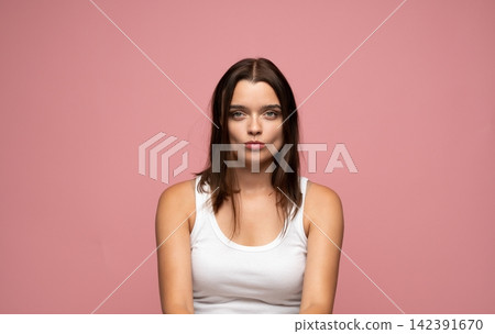 Young woman pouting lips with duck face expression, creating a playful and cheeky attitude posing on a pink background 142391670