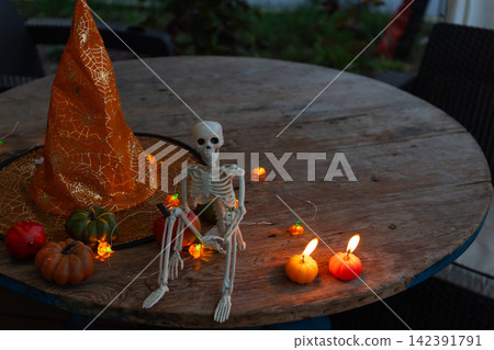 Cozy Halloween Veranda Decor: Skeleton, Pumpkins, and Warm Lights for Autumn Evenings 142391791