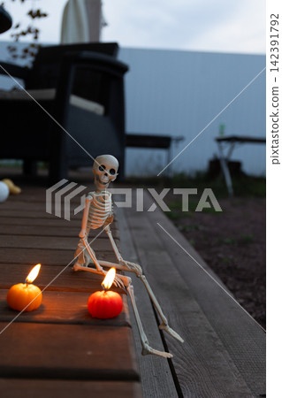 Candlelit Skeleton Prop in Twilight Halloween Scene on Rustic Deck Candlelit Skeleton Prop in Twilight Halloween Scene on Rustic Deck 142391792