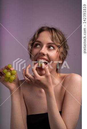Young woman enjoying fresh green grapes, looking up, promoting healthy eating and natural beauty concept Young woman enjoying fresh green grapes, looking up, promoting healthy eating and natural beauty concept 142391819