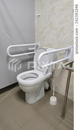 Accessible toilet with safety grab bars designed for elderly patients in a clean modern public restroom area. Accessible toilet with safety grab bars designed for elderly patients in a clean modern public restroom area. 142391846
