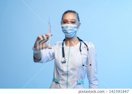 Healthcare professional holding vaccine syringe, doctor wearing mask and protective eyewear, medical treatment and immunization concept Healthcare professional holding vaccine syringe, doctor wearing mask and protective eyewear, medical treatment and immunization concept 142391847