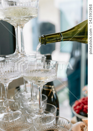 Champagne being poured into crystal glasses at a festive celebration with sparkling wine and romantic atmosphere Champagne being poured into crystal glasses at a festive celebration with sparkling wine and romantic atmosphere 142391968
