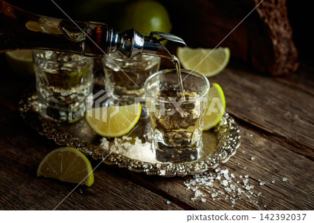 Tequila with salt and lime slices on a silver tray. Tequila with salt and lime slices on a silver tray. 142392037