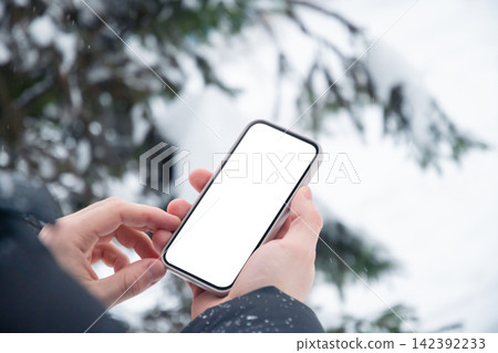 Hands using smartphone outdoors during winter snowfall Hands using smartphone outdoors during winter snowfall 142392233