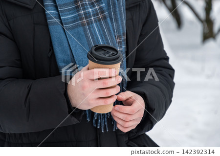 Man holding takeaway coffee cup outdoors in winter Man holding takeaway coffee cup outdoors in winter 142392314