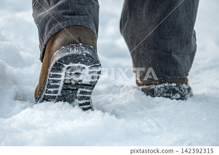 Winter boots walking through deep snow close up 142392315