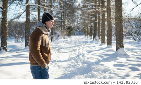 Young man walking alone in snowy winter park Young man walking alone in snowy winter park 142392316