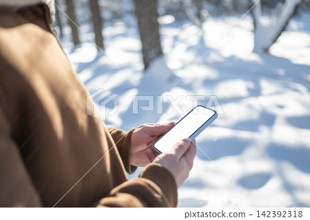 Man using smartphone outdoors in snowy winter park Man using smartphone outdoors in snowy winter park 142392318