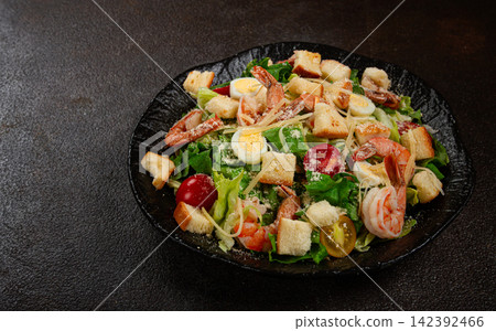 caesar salad with tiger prawns, shrimp salad, lettuce leaves, quail eggs, cherry tomatoes, parmesan cheese, on a black plate, caesar salad with tiger prawns, shrimp salad, lettuce leaves, quail eggs, cherry tomatoes, parmesan cheese, on a black plate, 142392466