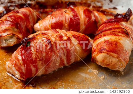 baked chicken breast, wrapped in bacon, on a baking tray. in the home kitchen.close-up. baked chicken breast, wrapped in bacon, on a baking tray. in the home kitchen.close-up. 142392500