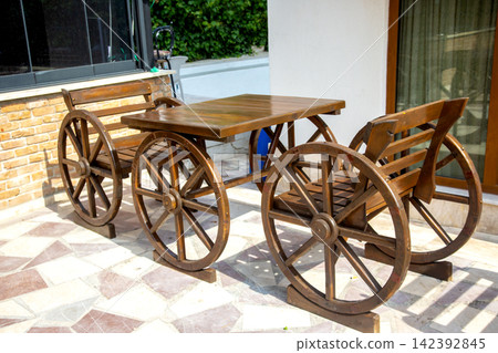 Wooden cart table and chairs placed outside a building in a sunny area Wooden cart table and chairs placed outside a building in a sunny area 142392845