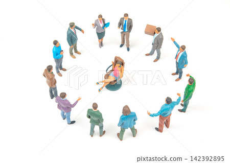 Miniature people in a meeting around a central figure seated in a chair 142392895