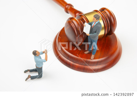 Miniature figures interact near a gavel on a simple white surface Miniature figures interact near a gavel on a simple white surface 142392897