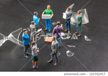 Miniature people gather around broken pieces and a box in a busy scene Miniature people gather around broken pieces and a box in a busy scene 142392917