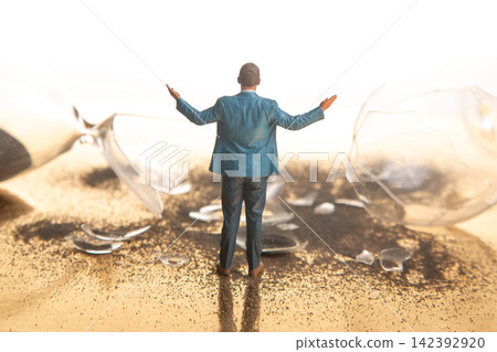 Miniature people standing by broken glass and spilled substance on gold surface Miniature people standing by broken glass and spilled substance on gold surface 142392920
