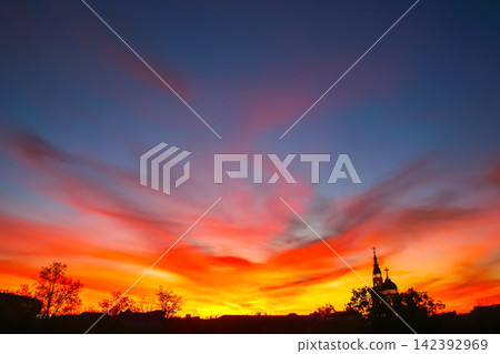 Sunset over the city with silhouettes of trees and buildings in the background 142392969