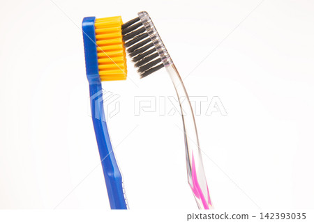 Two toothbrushes in close up view showing different bristle styles and colors in a bright setting Two toothbrushes in close up view showing different bristle styles and colors in a bright setting 142393035