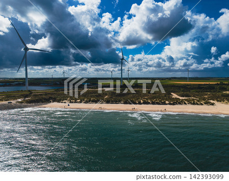 High angle wide horizontal aerial drone photograph of wind turbines, sandy beach, coastal sand dunes, and North Sea waves in Neeltje Jans, Zeeland, Netherlands on sunny summer day High angle wide horizontal aerial drone photograph of wind turbines, sandy beach, coastal sand dunes, and North Sea waves in Neeltje Jans, Zeeland, Netherlands on sunny summer day 142393099