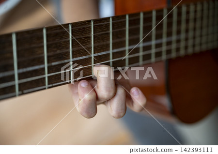 Closeup view of a child practicing playing classical guitar Closeup view of a child practicing playing classical guitar 142393111