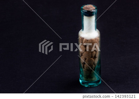 Vintage Glass Bottle with Old Pharmaceutical Tablets on Dark Background Vintage Glass Bottle with Old Pharmaceutical Tablets on Dark Background 142393121