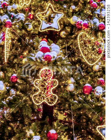 Festive Christmas Tree With Twinkling Lights, Red Ornaments, Snowy Branches And Illuminated Gingerbread Festive Christmas Tree With Twinkling Lights, Red Ornaments, Snowy Branches And Illuminated Gingerbread 142393258
