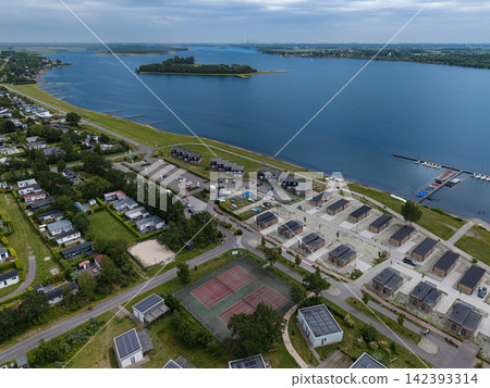 High angle wide horizontal aerial drone photograph of lakeside holiday resort, bungalows, tennis courts, sailing marina, and Lake Veere in Kamperland, Zeeland, Netherlands on cloudy summer day High angle wide horizontal aerial drone photograph of lakeside holiday resort, bungalows, tennis courts, sailing marina, and Lake Veere in Kamperland, Zeeland, Netherlands on cloudy summer day 142393314