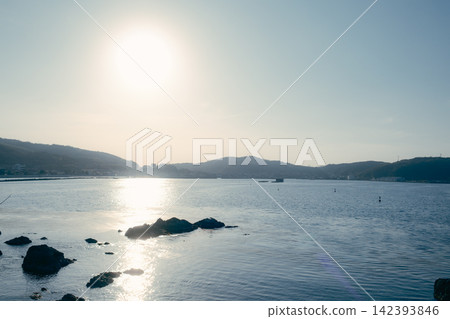 A tranquil sea and harbor scene, illuminated by the setting sun. A tranquil sea and harbor scene, illuminated by the setting sun. 142393846