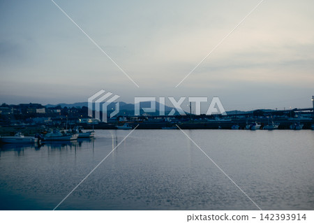 黃昏時分,一座斜張橋橫跨海港,與平靜的海面交相輝映。 黃昏時分,一座斜張橋橫跨海港,與平靜的海面交相輝映。 142393914