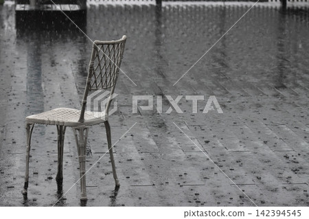 A deck being battered by heavy rain, chairs being battered by the rain. A deck being battered by heavy rain, chairs being battered by the rain. 142394545