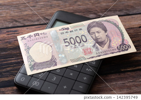 一張5000日元鈔票和一個計算器 一張5000日元鈔票和一個計算器 142395749