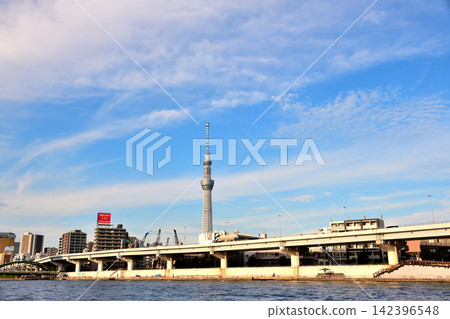 在湛藍的天空下,大都會高速公路與隅田川平行延伸。 在湛藍的天空下,大都會高速公路與隅田川平行延伸。 142396548