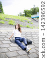 A woman strolling through a grassland or riverbank. 142396592