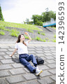 A woman strolling through a grassland or riverbank. 142396593