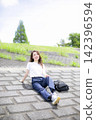 A woman strolling through a grassland or riverbank. 142396594