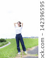 A woman strolling through a grassland or riverbank. 142396595