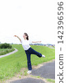 A woman strolling through a grassland or riverbank. 142396596