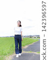 A woman strolling through a grassland or riverbank. 142396597