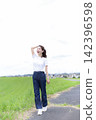 A woman strolling through a grassland or riverbank. 142396598