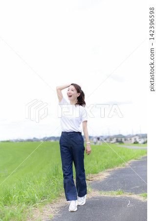 一位女子在草地或河岸邊漫步。 142396598
