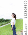 A woman strolling through a grassland or riverbank. 142396599