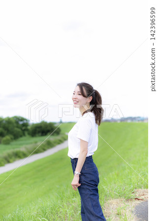 A woman strolling through a grassland or riverbank. A woman strolling through a grassland or riverbank. 142396599