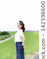 A woman strolling through a grassland or riverbank. 142396600