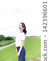 A woman strolling through a grassland or riverbank. 142396601