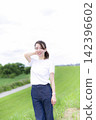 A woman strolling through a grassland or riverbank. 142396602
