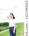 A woman strolling through a grassland or riverbank. 142396603